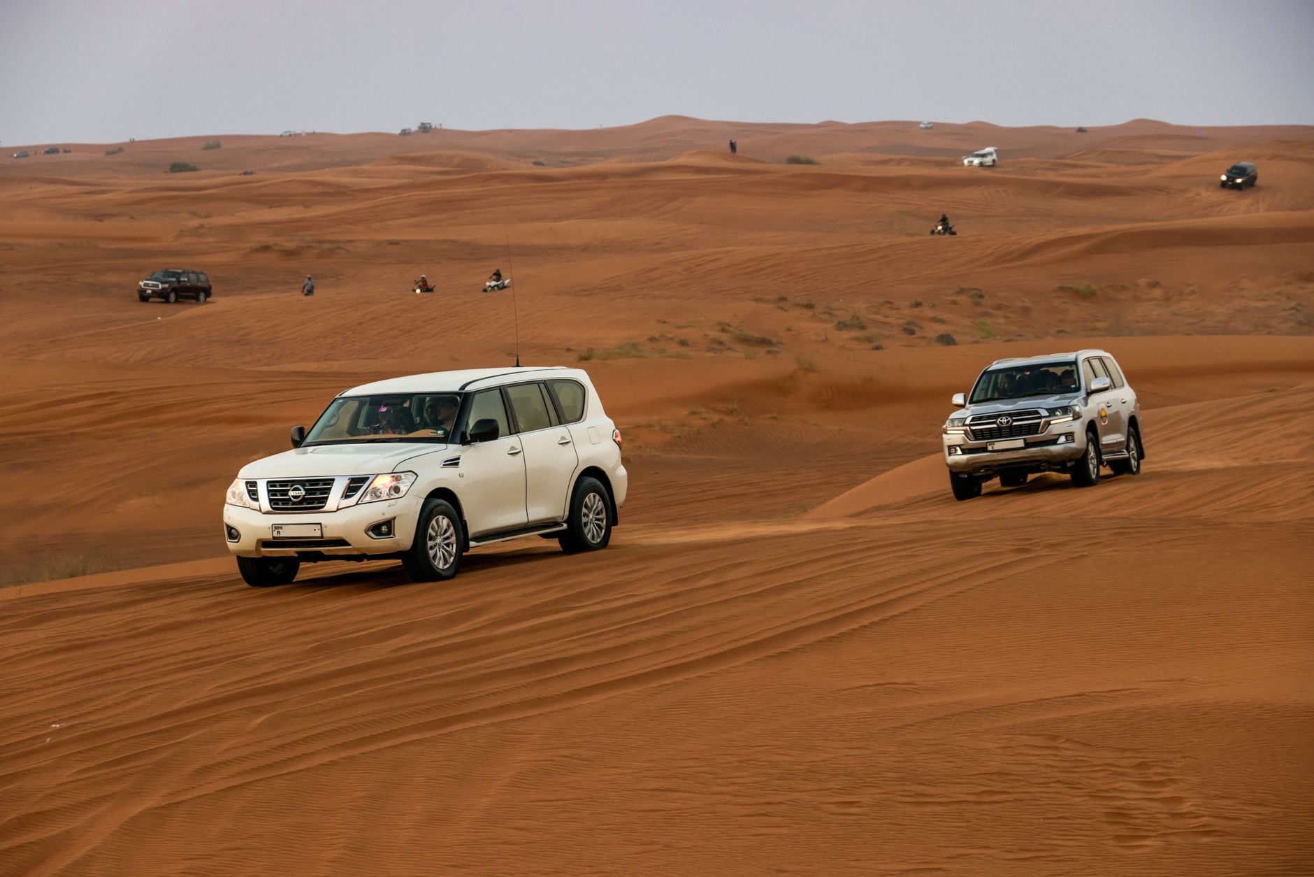 deux véhicules SUV roulant sur des dunes de sable dans un paysage désertique