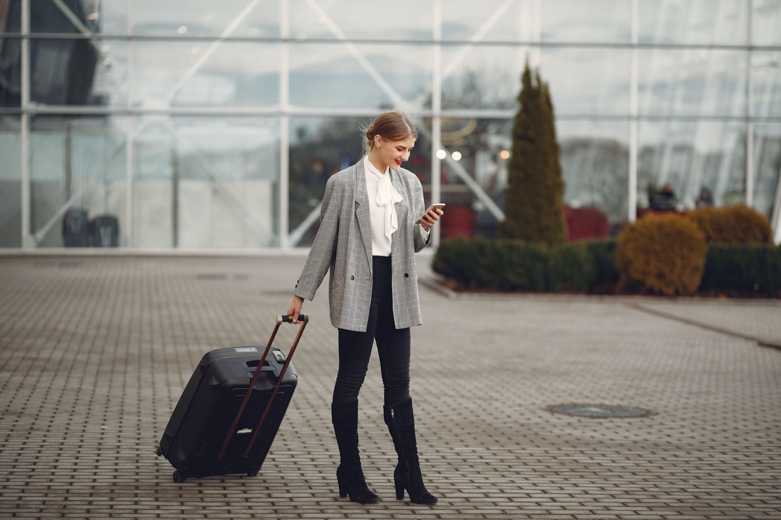 Touriste comparant les prix de location de voiture sur son smartphone à l'aéroport