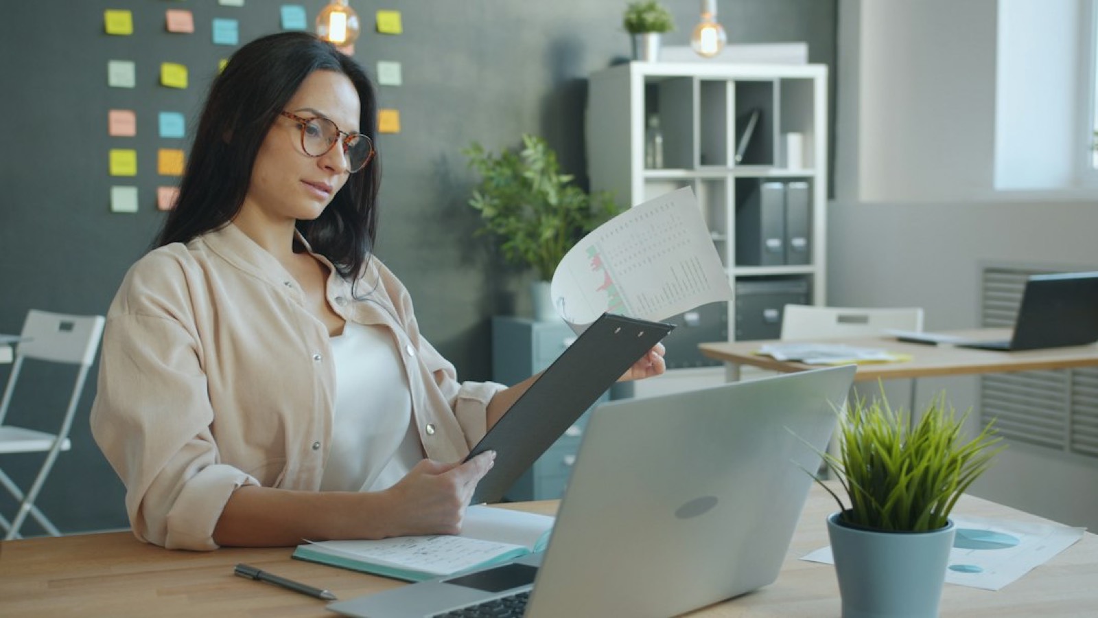 Personne assise à un bureau prenant des notes sur des documents avant un appel juridique