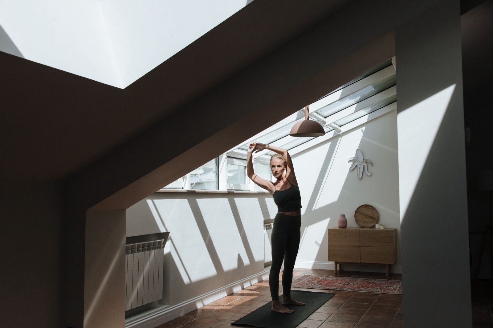 Femme s'étirant chez elle sur un tapis de sport avant une séance d'activité physique